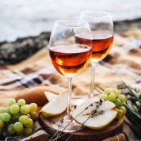two glasses of wine and summer fruits on the beach, sea and landscape in background, summer picnic, idea for outdoor weekend activity - food stock pictures, royalty-free photos & images