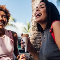 two happy female friends with ice cream cones at a palm tree - food stockfoto's en -beelden