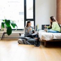 two happy young women having asian takeaway food at home - junk food stock pictures, royalty-free photos & images