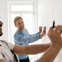 two male friends taking measurements using a measuring tape - home decoration stock pictures, royalty-free photos & images