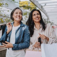two mature friends shopping at the mall holding bags - fashion stock pictures, royalty-free photos & images