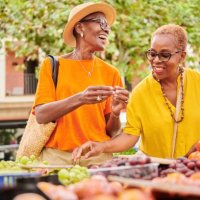 two mature women shopping together at an outdoor food market - travel stock pictures, royalty-free photos & images