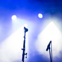 two microphone stands on a stage, under blue theatrical smoke and spotlights - concert stockfoto's en -beelden
