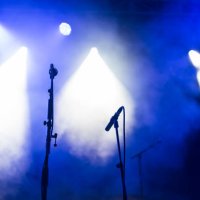 two microphones stands on a concert stage under blue and white spotlights - concert stock pictures, royalty-free photos & images