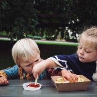 two toddlers sharing hot chips and tomato sauce at a picnic in the park - junk food stock pictures, royalty-free photos & images