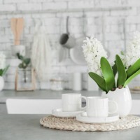 two white cups and vase of flowers on table. decor accessories in kitchen in light colors. - home decoration stockfoto's en -beelden