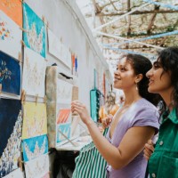 two woman admire paintings at a market stall as they vacation in europe - travel stock pictures, royalty-free photos & images