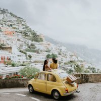 two woman stand in a vintage yellow fiat, and admire the view of positano, italy. - travel stock-fotos und bilder