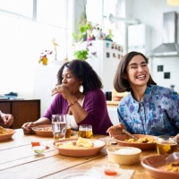 two women and man sitting at table eating takeaway curry together - junk food stock pictures, royalty-free photos & images