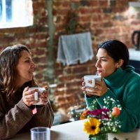 two women enjoying hot drink having conversation - coffee stock pictures, royalty-free photos & images