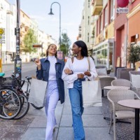 two women friends smiling with shopping bags walking in the city - fashion stock pictures, royalty-free photos & images
