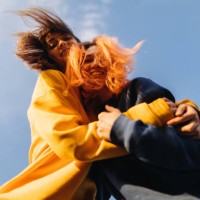 two women hugging at the blue sky background at the sunset - fashion stock pictures, royalty-free photos & images