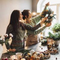 two women making christmas wreath using fresh pine branches and festive decorations. - home decoration stock pictures, royalty-free photos & images