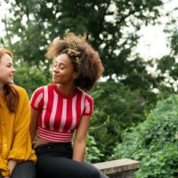 two women sat on wall - hairstyle stock pictures, royalty-free photos & images