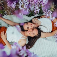 two young european twins with long dark hair lying on a picnic looking at the camera smiling faces close to each other top view through wisteria flowers - fashion stock pictures, royalty-free photos & images