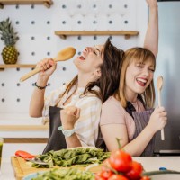 two young female friends cooking in the kitchen - food stock pictures, royalty-free photos & images