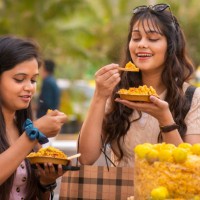 two young female friends eating indian street food (bhelpuri) at street market. - junk food stock pictures, royalty-free photos & images