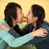 two young friends eating a hamburger. - junk food stock pictures, royalty-free photos & images