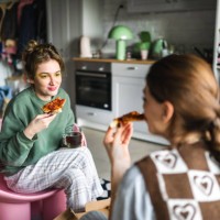 two young housemates eat pizza they ordered from outside together at home - junk food stock pictures, royalty-free photos & images