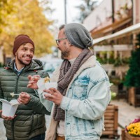 two young man eating fast food outdoors - junk food stock pictures, royalty-free photos & images