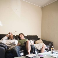 two young men, a gay couple, relaxing on a sofa - junk food stock pictures, royalty-free photos & images