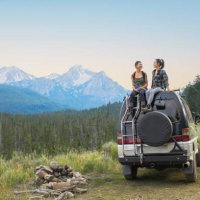 two young woman on top of camper van in remote mountain landscape - travel stock pictures, royalty-free photos & images