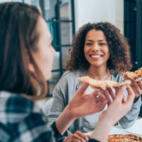 two young women eating pizza together at home. - junk food stock pictures, royalty-free photos & images