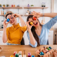 two young women holding up easter eggs - home decoration stock pictures, royalty-free photos & images