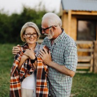 un couple de personnes âgées heureux est en vacances et passe la soirée devant leur cabine, se réchauffant avec une couverture et profitant du coucher du soleil - garden decoration photos et images de collection