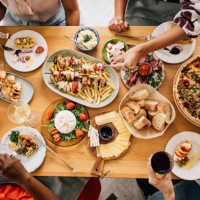una vista desde arriba de una mesa llena de deliciosa comida consumida por un grupo irreconocible de personas multiétnicas - food fotografías e imágenes de stock