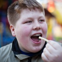 unhealthy eating: redhead overweight teenage boy eats french fries - junk food stock pictures, royalty-free photos & images