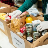 unrecognizable volunteer organizing donations in boxes wearing protective gloves - food stock pictures, royalty-free photos & images