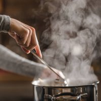 unrecognizable woman making lunch in the kitchen and stirring soup. - food stock pictures, royalty-free photos & images