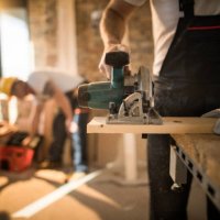 unrecognizable worker cutting plank with circular saw at construction site. - home decoration stock pictures, royalty-free photos & images