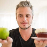 usa, new jersey, jersey city, man weighing green apple against cup cake - junk food stock pictures, royalty-free photos & images