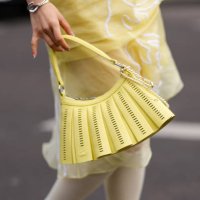 Valerie Zhang wears a shiny bright yellow Lacoste leather bag, outside Lacoste, during the Paris Fashion week Women's Fall/Winter 2025-2026 on March...