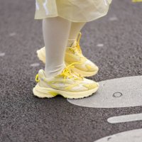 Valerie Zhang wears white knee high socks, bright yellow sneaker shoes, outside Lacoste, during the Paris Fashion week Women's Fall/Winter 2025-2026...