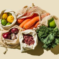 variety fresh of organic fruits and vegetables and healthy vegan meal ingredients in reusable eco cotton bags on beige background . zero waste shopping concept. healthy food, clean eating, eco friendly, no plastic. flat lay, 