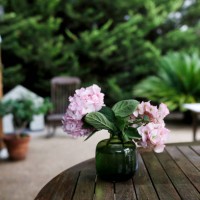 vase with pink hydrangeas on a wood garden table - garden decoration stock-fotos und bilder