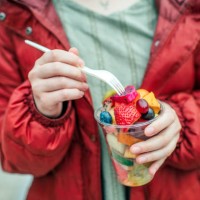 vegan woman eating fruit salad outdoors - junk food stock pictures, royalty-free photos & images