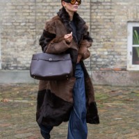 Vera van Erp wears brown black two tone fur coat, Manu Atelier bag, denim jeans, sunglasses outside TG Botanical during the Copenhagen Fashion Week...