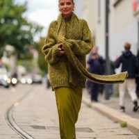 Veronica Ferraro wears gold earrings, dark green cotton knit oversized sweater, dark green cotton knit, dark green cotton knit oversized scarf, dark...