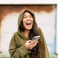 verticale de jeune femme retenant le téléphone intelligent et riant - fashion photos et images de collection