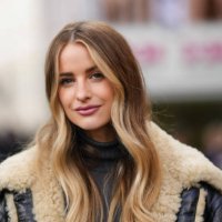 Victoria Magrath wears a dark gray ribbed wool turtleneck pullover, a black shiny leather with beige sheep fur details oversized aviator coat,...