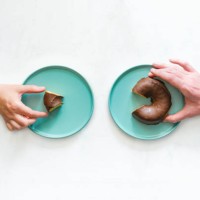 view from above of a woman's hand and a man's hand holding up two different sized pieces of a chocolate bun. concept of labor inequality. - junk food stock pictures, royalty-free photos & images