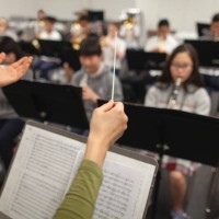 view of band instructor teacher conductor hands leading music performance orchestra of junior high school teenager students practicing in school classroom together in a group of people - concert stock pictures, royalty-free p