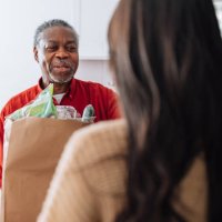 volunteer delivering food for senior man - food stock pictures, royalty-free photos & images