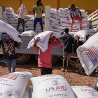 Volunteers at the Zanzalima Camp for Internally Displaced People unload 50 kilogram saks of Wheat flour that were a part of an aid delivery from...