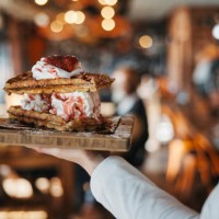 waffles, ice cream and dessert in hand, fast food restaurant service with person and sweet treat for customer. catering, hospitality and cuisine with dairy treat on wooden plate, luxury and delicious - junk food stock picture
