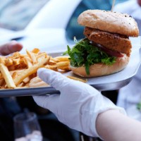 Waitress at The Haus restaurant serves burgers and fries with gloves during the Corona crisis. Photo: Annette Riedl/dpa-Zentralbild/ZB